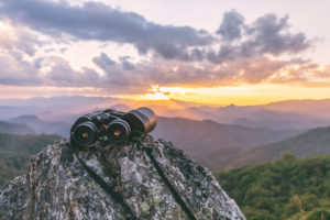 Binoculars sitting on a rock overlooking a mountain range